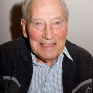 Portrait of elderly man in zip-up sweater at the celebration event.