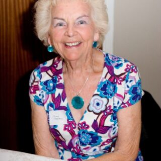 Jean Campbell seated at a table, smiling warmly.