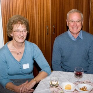 Two adults seated side by side at a table, smiling.