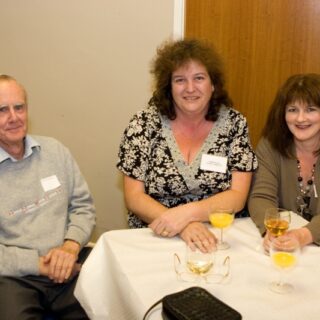 Three attendees seated around a small table with drinks.