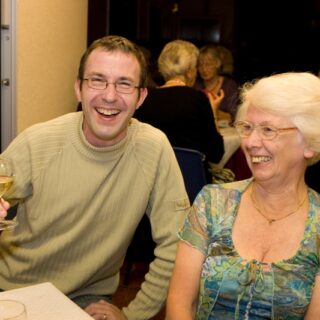 Two people seated at a table, smiling during a lively indoor event.