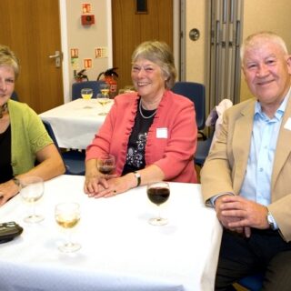 Three people seated at a table during a social event.