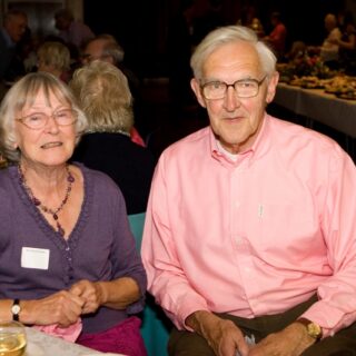 Two people seated together at a festive indoor event.