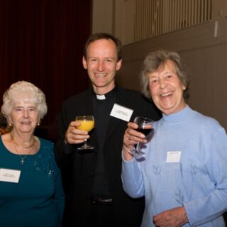 Jean, Andrew, and Eileen Godfrey standing together with drinks at the Basinga 35th anniversary.