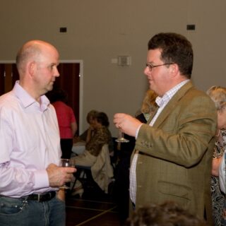 Two guests chatting with drinks in hand.