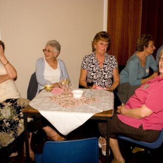 Guests seated around a table, talking and enjoying refreshments during the Basinga’s 35th anniversary event.