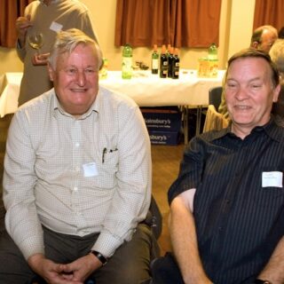Guests seated and talking near a drinks table stocked with bottles at the Basinga’s 35th anniversary.